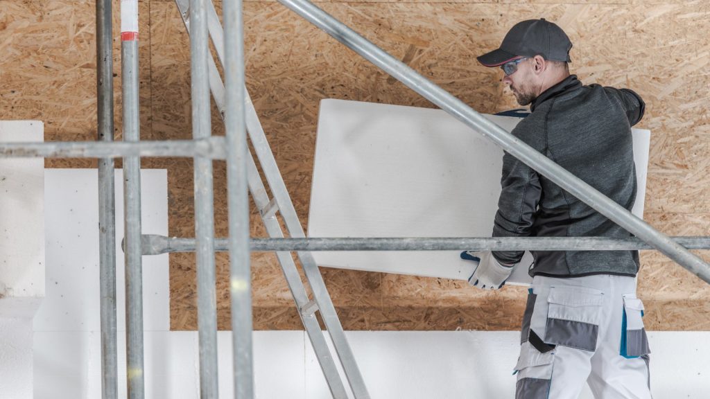 Homme à lunettes plaçant un panneau d'isolation
